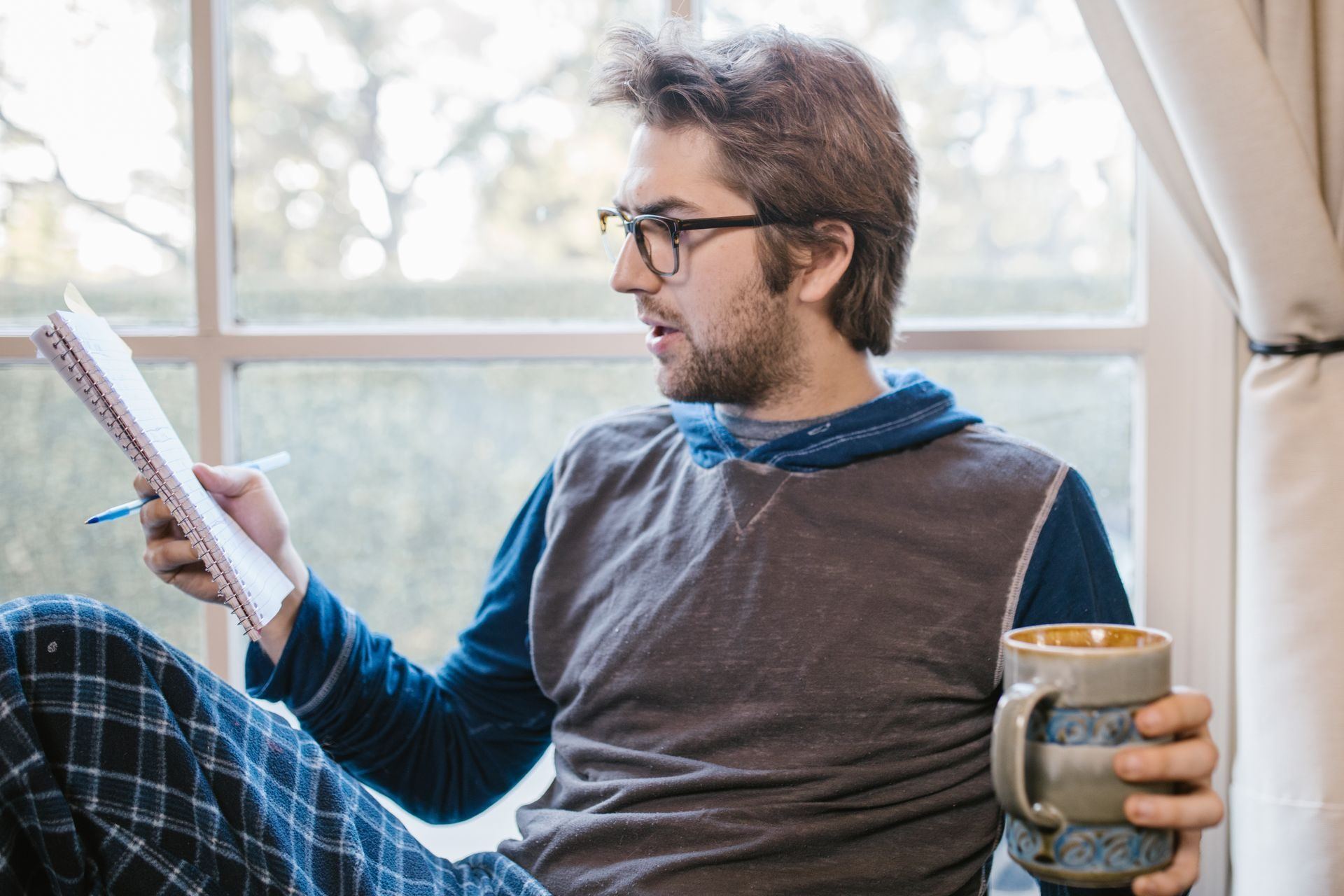A man with a mug reading a notebook